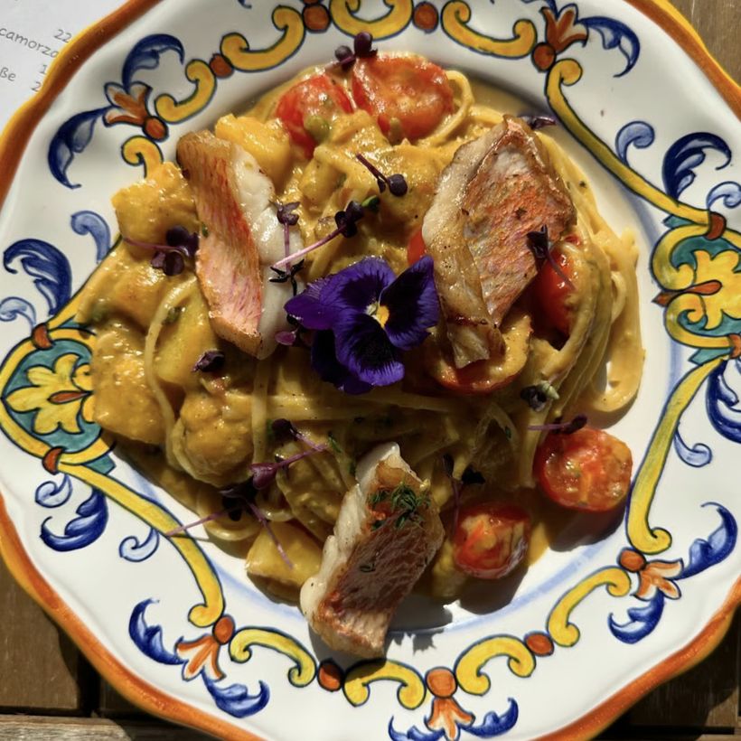 Pasta mit gebratenem Fisch, Kirschtomaten und essbarer Blüte